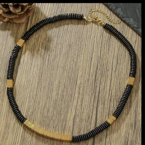 Macro view of retro necklace featuring black coconut shell discs and gold copper alloy blocks