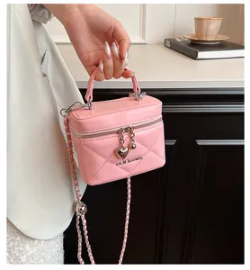 Elegante primo piano di una borsa a scatola trapuntata rosa con ciondolo a cuore d'oro e catena