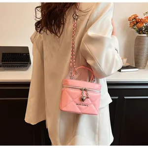 Primo piano di una borsa a scatola trapuntata rosa con ciondolo a cuore indossata
