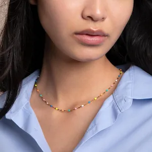 Close-up of a delicate stainless steel necklace with colorful rainbow enamel beads on a model
