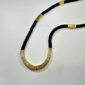 Close-up detail of a stylish necklace with black coconut shell and golden copper alloy beads.