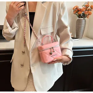 Dettaglio di una borsa a mano trapuntata rosa con ciondolo a forma di cuore e tracolla a catena