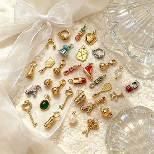 Detailed macro shot of various 18K gold-plated DIY jewelry charms on white fabric.