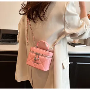 Borsa a scatola trapuntata rosa con manico e tracolla a catena indossata da una modella.