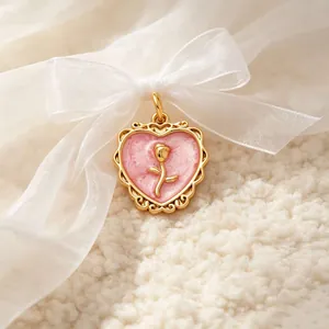 Close-up of vintage heart pendant with gold rose detail on pink marble effect base