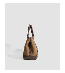 Détail latéral d'un grand sac fourre-tout en laine à chevrons avec des anses en cuir marron
