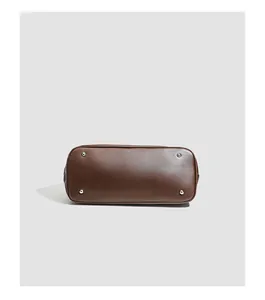 Vue du dessous d'un sac à main en cuir marron avec quatre clous argentés