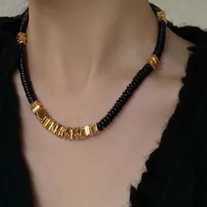 Close-up detail of a minimalist black coconut shell and gold plated copper alloy necklace