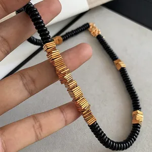 High-detail shot of retro black coconut shell and golden copper alloy bead necklace