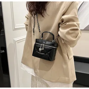 Dettaglio di una borsa a scatola nera trapuntata con ciondolo a cuore e tracolla