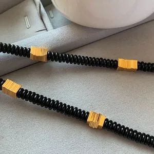 Close-up of natural black coconut shell necklace with gold-toned ridged metal spacers