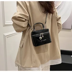 Vista dettagliata di una borsa a scatola trapuntata nera con ciondolo a cuore su una modella