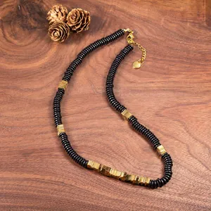 Detail of natural black coconut shell and gold copper alloy beads on a wooden background