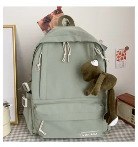 Detailed view of a mint green student backpack featuring a cute green frog keychain charm
