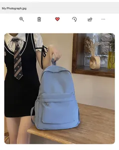 Detailansicht eines hellblauen Rucksacks, gehalten von einem Modell an einem Holztisch