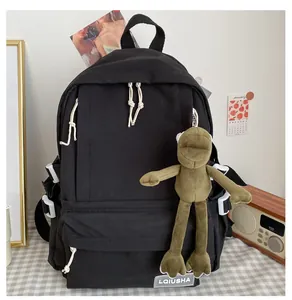 Detail of a black minimalist school backpack with a cute green frog plush keychain