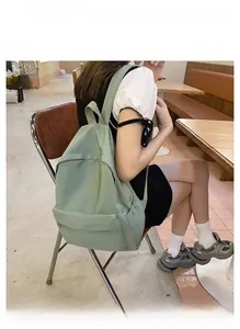 Nahaufnahme eines minimalistischen hellgrünen Rucksacks, den ein Model im Café trägt