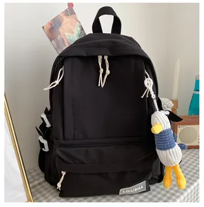 Detail view of a black large-capacity school backpack with a cute duck plush charm