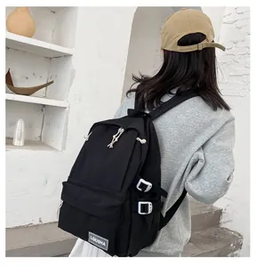 Back view of a black minimalist large capacity backpack worn by a model in a studio