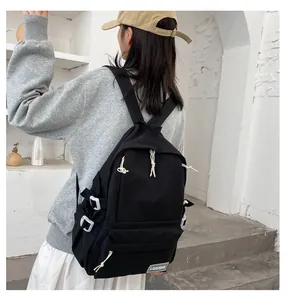 Back view of an Asian model wearing a minimalist black large capacity college style schoolbag