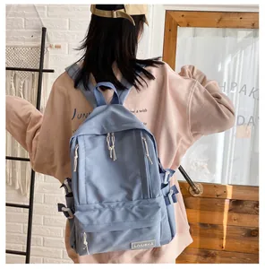 Lifestyle view of a solid blue school backpack worn by a model in a cozy setting.