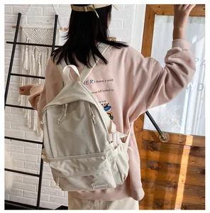 Back view of a minimalist beige Korean style college backpack worn by a student