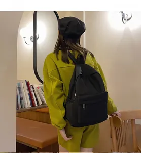 Rückansicht eines minimalistischen schwarzen Rucksacks, getragen von einem Modell in Innenräumen