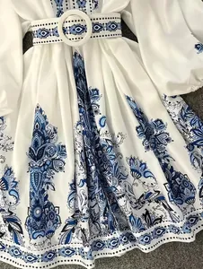 Detailed close-up of white bohemian paisley print dress with round buckle waist belt