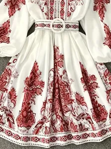 Detailed view of bohemian floral print and waist belt on white long sleeve dress