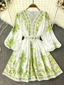 Detailed view of white V-neck dress with green bohemian floral print and matching belt.