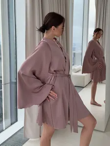 Vue latérale d'un peignoir satin rose poudré avec larges manches évasées et ceinture.