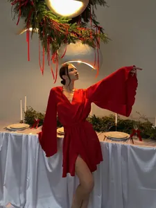 Femme élégante portant un peignoir rouge à manches cloches dans un décor de fête de Noël.