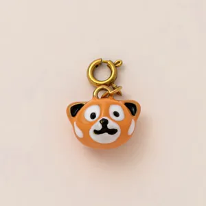 Dettaglio ravvicinato di un ciondolo a forma di panda rosso con chiusura dorata per borse.