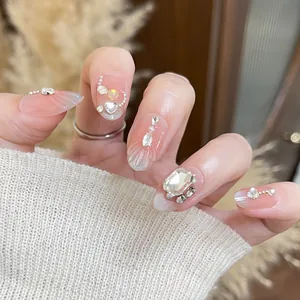 Detailed close-up of luxury nude pearlescent press-on nails with rhinestone accents