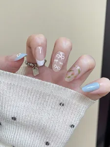Detailed view of short oval press-on nails with delicate floral and bow designs.