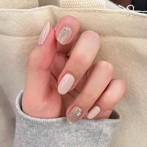 Close-up of elegant nude short oval press-on nails with pearl and rhinestone details