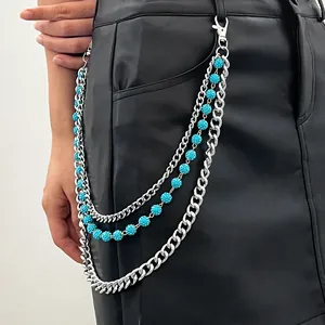 Dettaglio di catena da vita argento multistrato con perline blu su gonna di pelle.