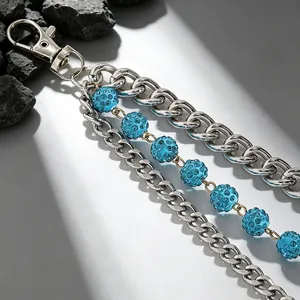 Dettaglio di catena da pantalone argento multistrato con perle di strass blu e maglie punk.