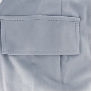 Macro view showing the stitched pocket flap on a light blue slim fit dress fabric