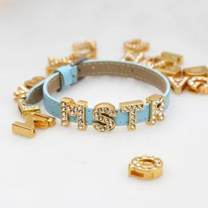 Detailed view of 8mm gold rhinestone alphabet beads sliding on a light blue DIY strap.