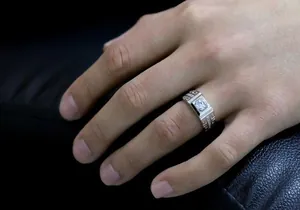 Close-up of silver men's ring with square zircon and greek key pattern on hand.