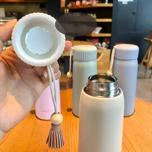 Close-up of the leak-proof lid and leather tassel detail on a pastel thermos bottle