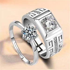 Macro view of silver couple rings with sparkling zircon stones and Greek key pattern.