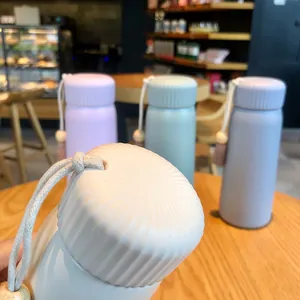 Close-up showing the ridged cap and tassel detail of a matte pastel insulated thermos bottle