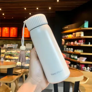 Close-up of minimalist white vacuum insulated water bottle with a tassel cord.