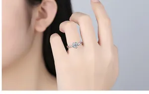 Close-up of elegant silver flower ring with twisted band worn on a model's finger.