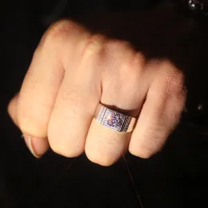 Macro view of a masculine silver-tone ring with a sparkling purple zircon stone.