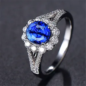 Macro view of an elegant oval blue zircon ring featuring a sparkling white stone halo
