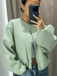 Mirror selfie of a woman wearing a soft mint green zip-up bomber jacket outfit