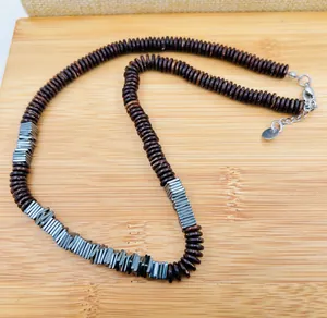 Detail of natural coconut shell beads and metallic rectangular accents on a necklace.